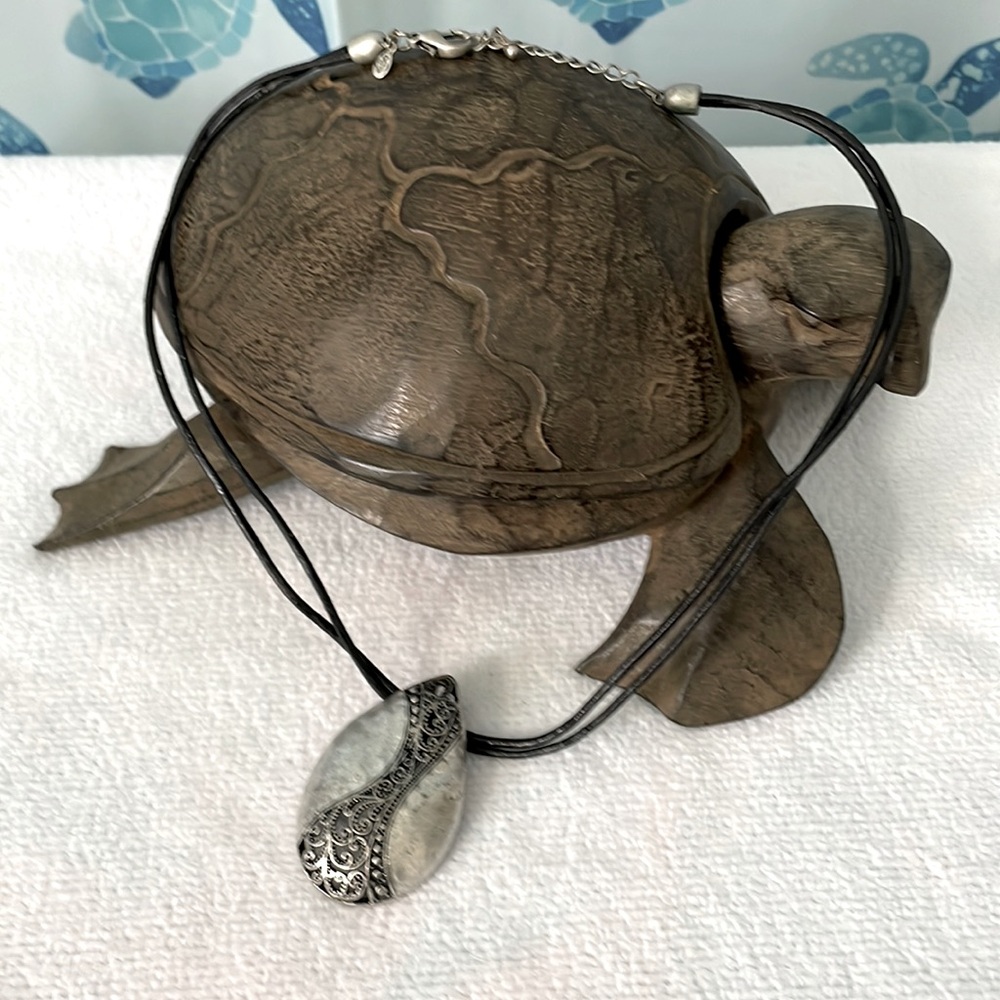 Black leather corded adjustable necklace with silver/black pendant.